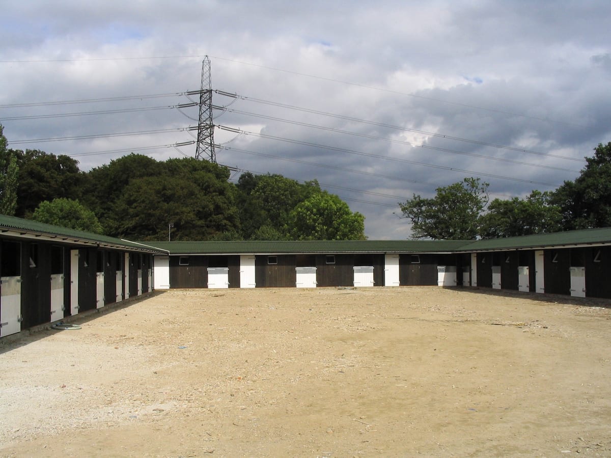 Large timber stable and tack room complex built around three sides of a yard